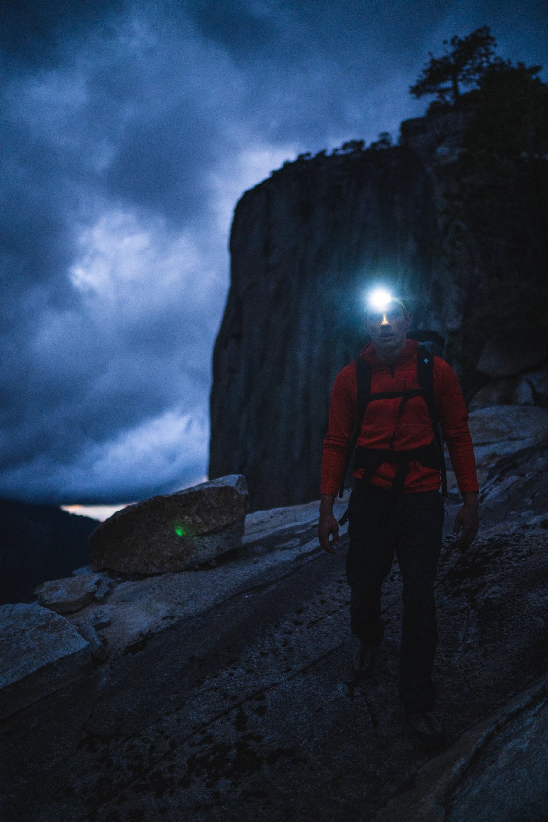 a man walking off the mountain at dusk with a headlamp on  